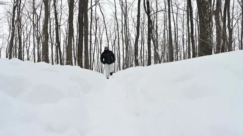 Man climbs steep snowy trail, showcasing determination and winter endurance Stock Footage 338414361