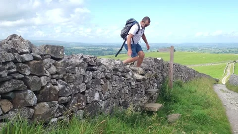 Man climbs stile over wall, Ingleton, North Yorkshire UK Stock Footage 245633745