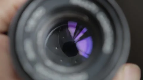 A man close down the aperture/diaphragm from vintage camera lens limiting the li Stock Footage 169975832