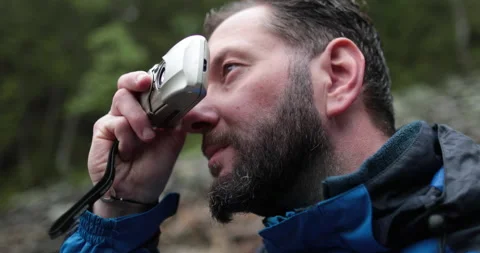 A man, close-up portrait, takes a photo of a landscape with a small camera Stock Footage 243605341
