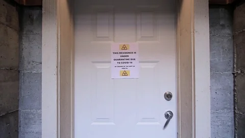 A man closes a door with a self isolating residence with a quarantine sign on 스톡 동영상 127143940