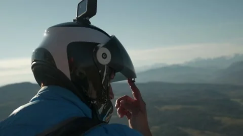 The man closes the helmet visor and prepares to jump off a cliff with parachutes 스톡 동영상 171637196