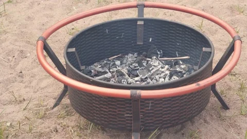 A man closes the lid of a fire pit with smoldering wood. Video stock 157288119