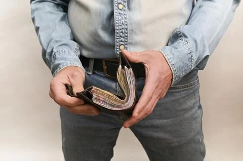 Man closes open wallet full of cash, symbolizing a good income, monetary Stock Photos