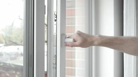 The man closes the PVC plastic window and turns the handle on the window frame. Stock Footage 255117921