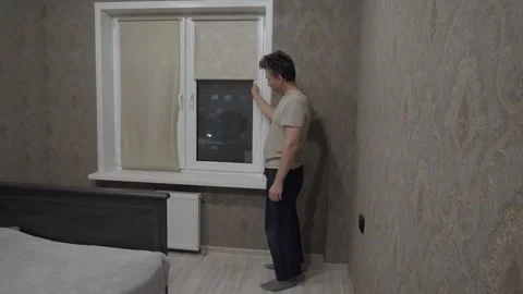 Man closes the roller blinds Stock Footage 337799816