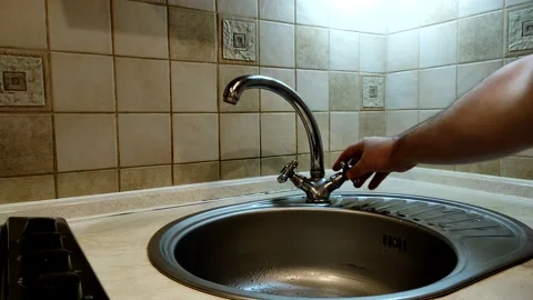 A man closes a tap in the kitchen from which water is dripping. Stock Footage 143161483