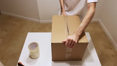 Man closing and sealing package with tape and utility knife Stock Footage 327067296