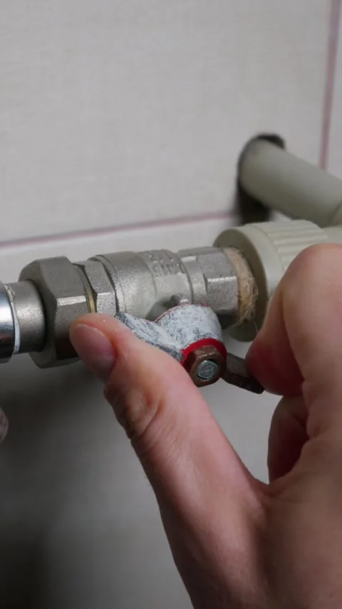 Man Closing Ball Valve for Heating System Maintenance in Residential Home Stock Footage 339213294