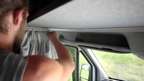 Man closing the curtains inside his caravan Stock Footage 135381612