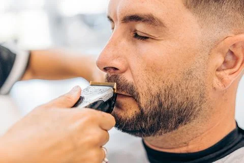 Man closing the eyes while is being shaved in a barbershop Stock Photos