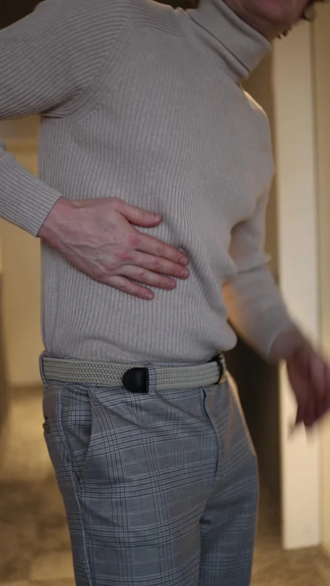 A man clutches his lower back with both hands, exhibiting a clear sign of discom Stock Footage 292515255