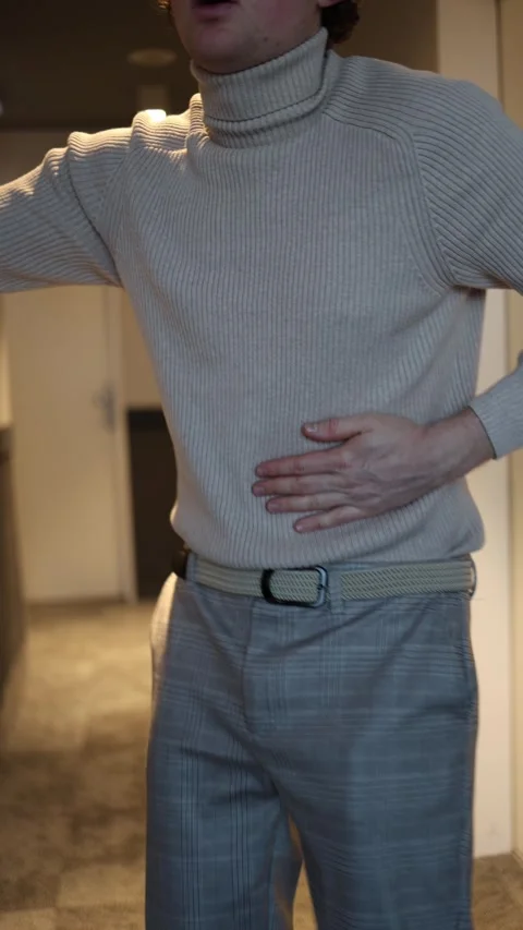 A man clutches his stomach with both hands, showing visible signs of discomfort. Stock Footage 292514577