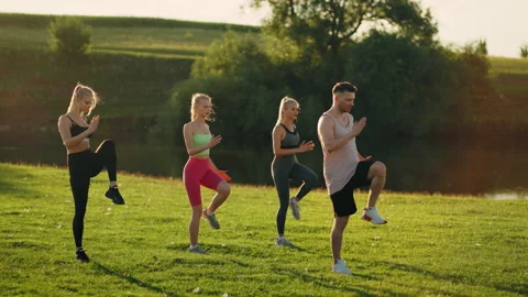 Man coach is showing physical exercise for group of young sporty women in park Stock Footage 205886222