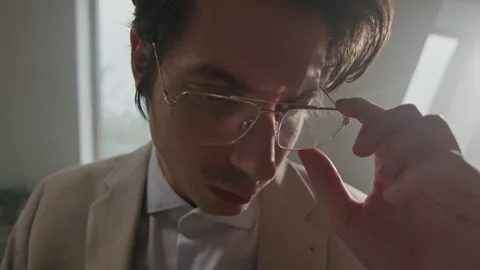 Man in coat adjusting eyeglasses while deep in thought at indoor location Stock Footage 319955309
