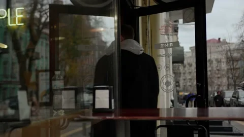 Man in a coat enters a restaurant through a glass door Stock Footage 221184504