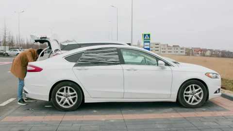 Man in coat opened trunk of his car looking through it for items. He searches Stock Footage 268908217