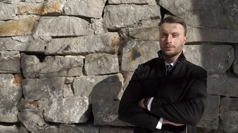 Man in a coat is standing by the wall 스톡 동영상 88164159