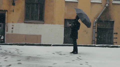 Man in coat with umbrella standing under snow holding plastic cup with coffee Stock Footage 74894433