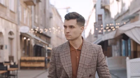 A man in a coat is walking down the street. Man takes off his glasses Video stock 243826647