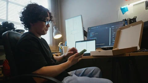 Man Coding on Laptop, Browsing Smartphone and Eating Pizza Stock Footage 338423950