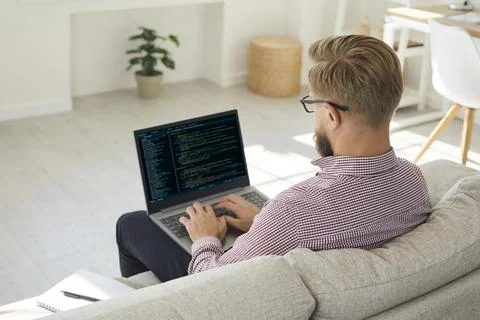 Man coding on laptop at home office, remote software developer working online Stockfoto's