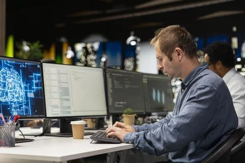 Man coding on PC in startup office, refining deep learning models 스톡 사진