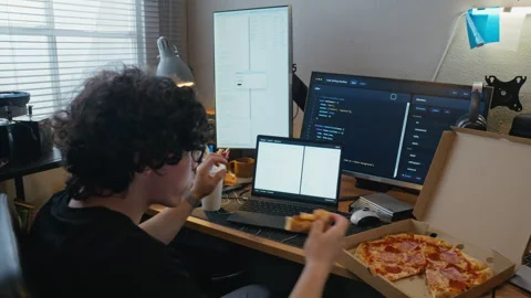 Man Coding Software on Laptop and Eating Pizza in Home Office Stock Footage 338423587