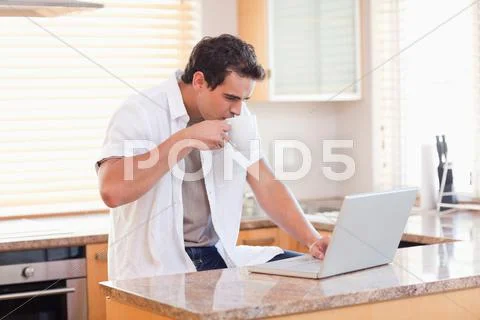 Man with coffee and laptop in the kitchen Stock-Fotos
