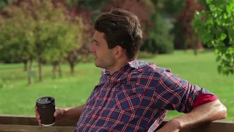 Man with coffee on a bench in the park Stock Footage 252679818