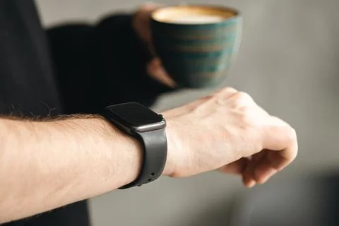 A man with coffee checking stylish smart watch, close up. Stock Photos