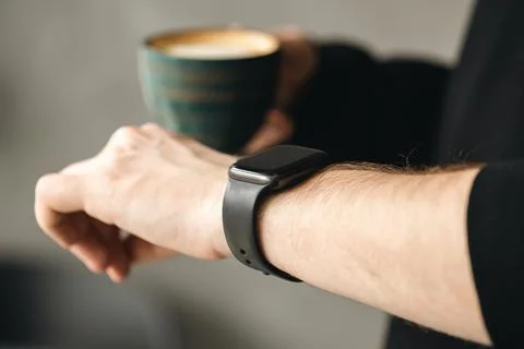 A man with coffee checking stylish smart watch, close up. Stock Photos