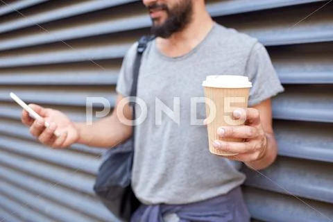 Man with coffee texting on smartphone in city Stock Photos