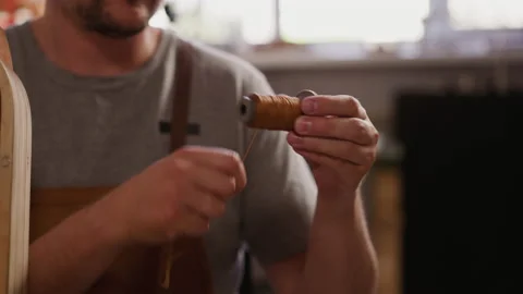 Man coils waxed thread for leather sewing in craft workshop Stock Footage 228546860