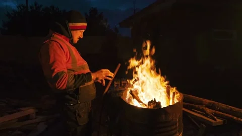 A man is cold and warming himself by the fire at night. Stock Footage 238479214