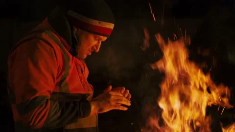 A man is cold and warming himself by the fire at night. Stock Footage 238479351
