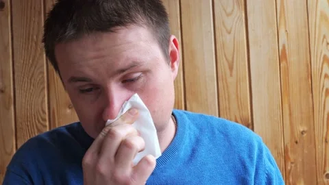 A man with a cold coughs and blows his nose into a handkerchief. He 's wearing a Stock Footage 166964118
