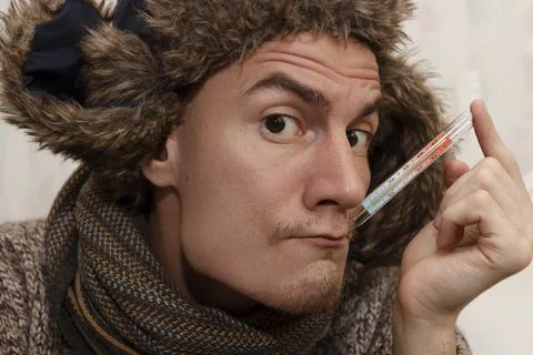 Man with cold measuring temperature with thermometer 스톡 사진