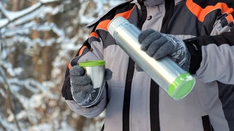 Man in the cold pours hot tea from a thermos into a mug. Hand with a mug of h Stock Footage 101012981