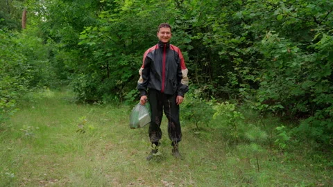 Man collect garbage in forest in package, looking at camera smile Stock Footage 158124379