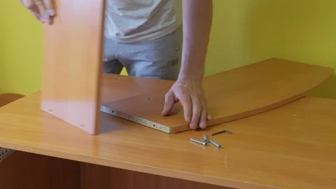 Man is collecting parts of computer table screwing shelf screwdriver, closeup. Stock Footage 124859974