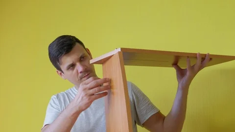 Man is collecting parts of computer table screwing shelf screwdriver, closeup. Video stock 125039847