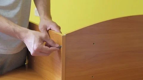 Man is collecting parts of computer table screwing shelf screwdriver, closeup. Stock Footage 129421261