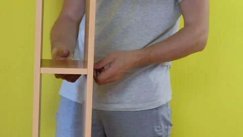 Man is collecting parts of computer table screwing shelf using screwdriver. 스톡 동영상 129423988