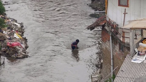 Man collecting rocks in a polluted river Видео 75887214