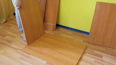 Man is collecting table on floor joining chipboard parts wooden colour. Stock Footage 125038991