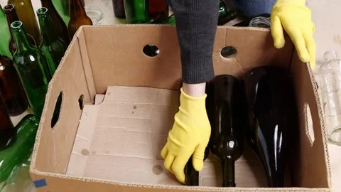 A man collects empty glass bottles and jars in a recycle box at home. Glass 库存影片 292836133