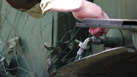 Man collects hot water from under tap into metal pelvis. Video stock 196009535