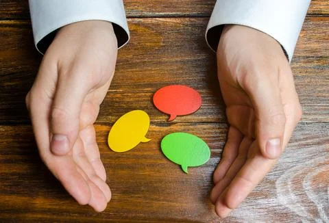 A man collects multicolored speech bubbles in his hands. Listen to other op.. Stock Photos