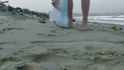 A man collects plastic garbage on the beach. Video stock 151628569